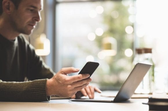 man looking at phone and computer