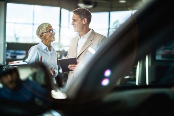 car buyer and salesperson shaking hands in a dealership showroom