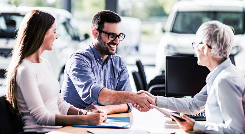 couple buying a car from a dealership saleswoman