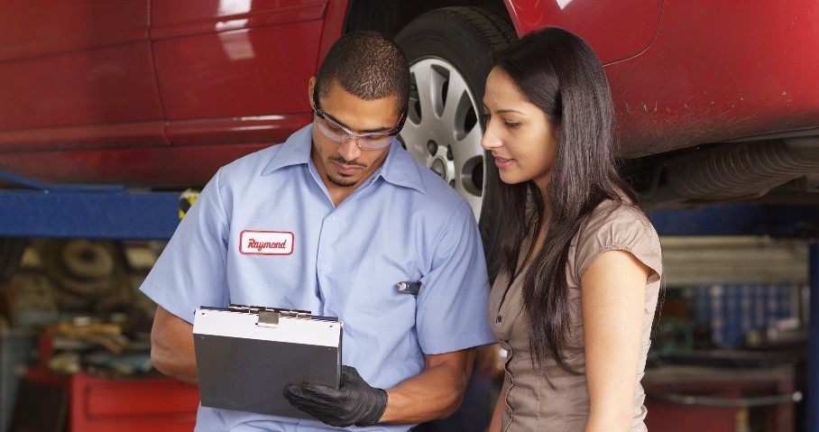 Vehicle service professional and a dealership customer looking over paperwork in a service bay